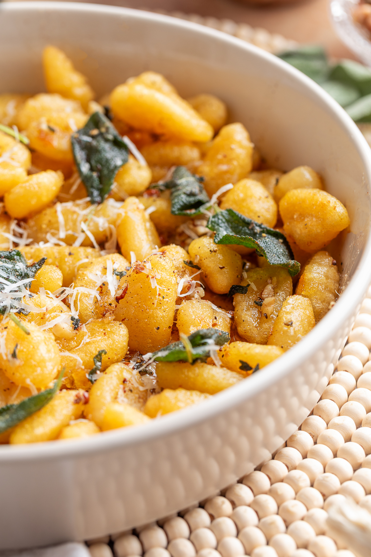 Pan-fried gnocchi with sage brown butter, Parmesan and crisp sage leaves. Close-up of pan-fried potato gnocchi with crisp sage leaves, grated Parmesan and toasted nuts.