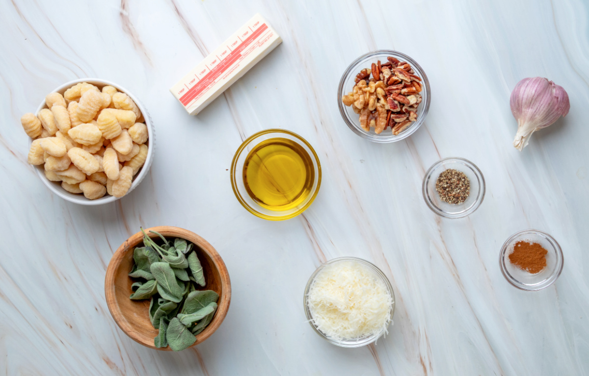 Ingredients for crispy gnocchi with sage brown butter, toasted nuts and Parmesan. Potato gnocchi, fresh sage, butter, olive oil, Parmesan, walnuts, pecans, garlic, nutmeg and black pepper.
