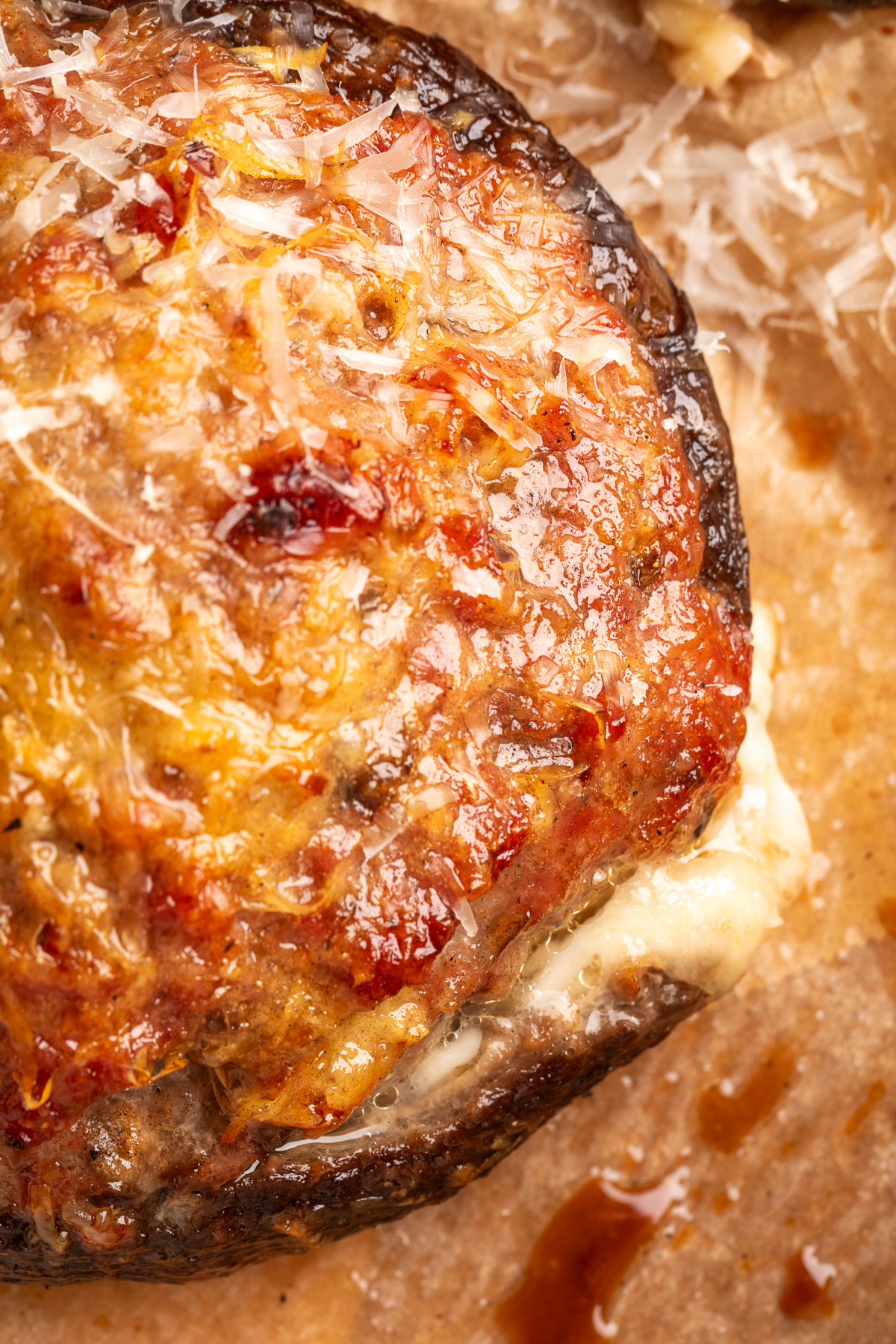 Close-up of sweet Italian sausage and Parmesan over a grilled portobello with mozzarella melted underneath. Sausage stuffed portobello mushroom with browned Parmesan and melted mozzarella underneath