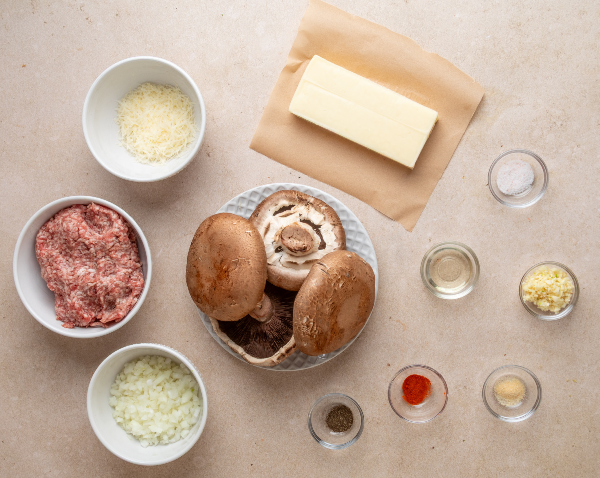 Portobello mushrooms, sweet Italian sausage, mozzarella, Parmesan, onion, garlic and seasonings ready for stuffing. Ingredients for grilled sausage stuffed portobello mushrooms including Italian sausage, portobellos, mozzarella and Parmesan