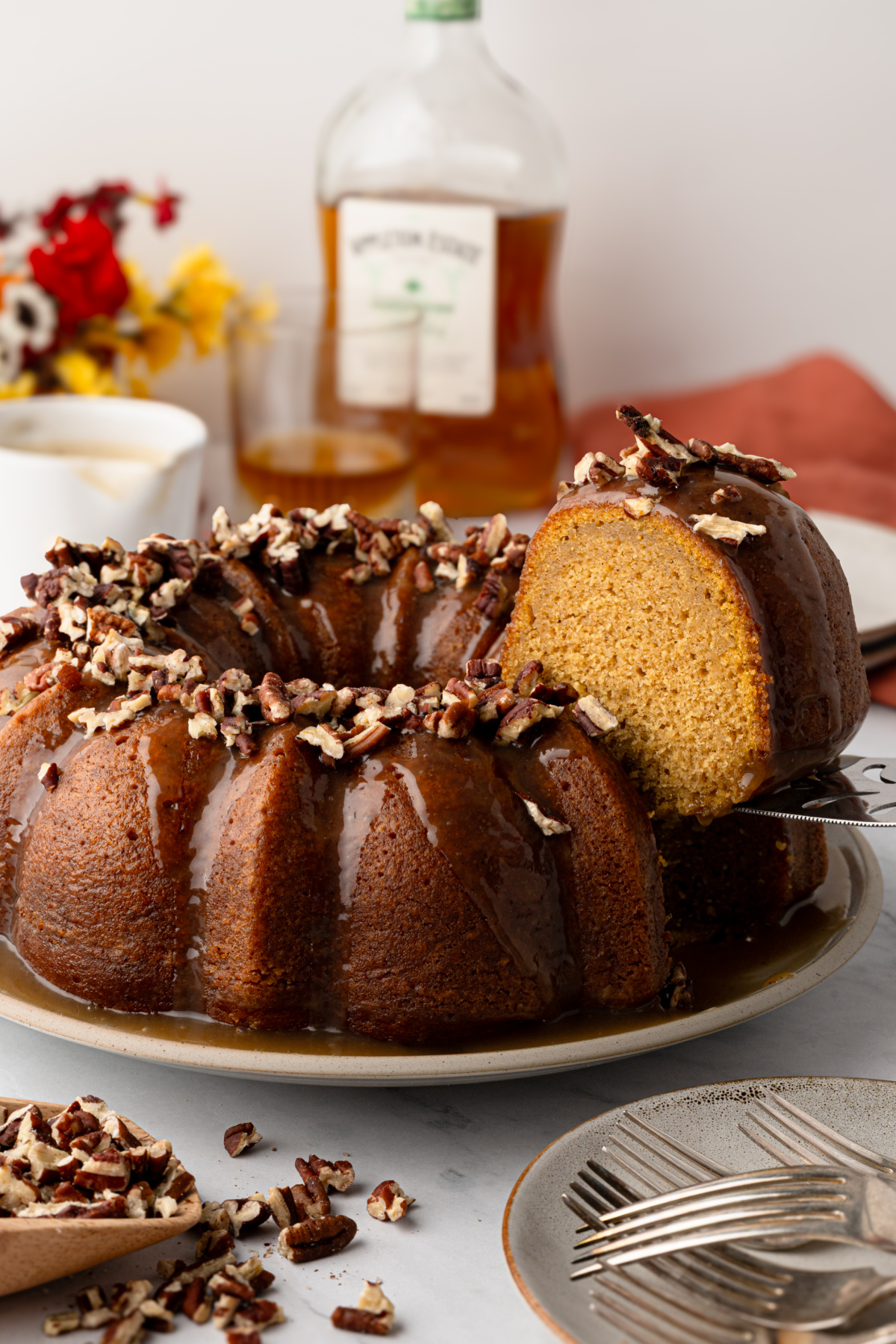 Roasted sweet potato Bundt cake made with brown butter and dark rum, finished with buttered rum caramel and toasted pecans. Sweet potato Bundt cake with buttered rum caramel glaze, toasted pecans and a slice cut to show the soft interior.