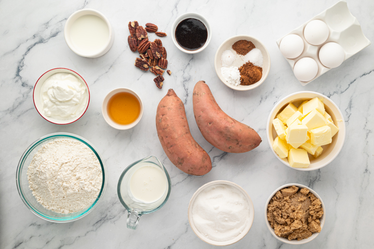 Ingredients used to make roasted sweet potato Bundt cake with brown butter, dark rum caramel and toasted pecans. Ingredients for sweet potato Bundt cake including sweet potatoes, butter, eggs, flour, sugars, sour cream, milk, pecans and seasonings.