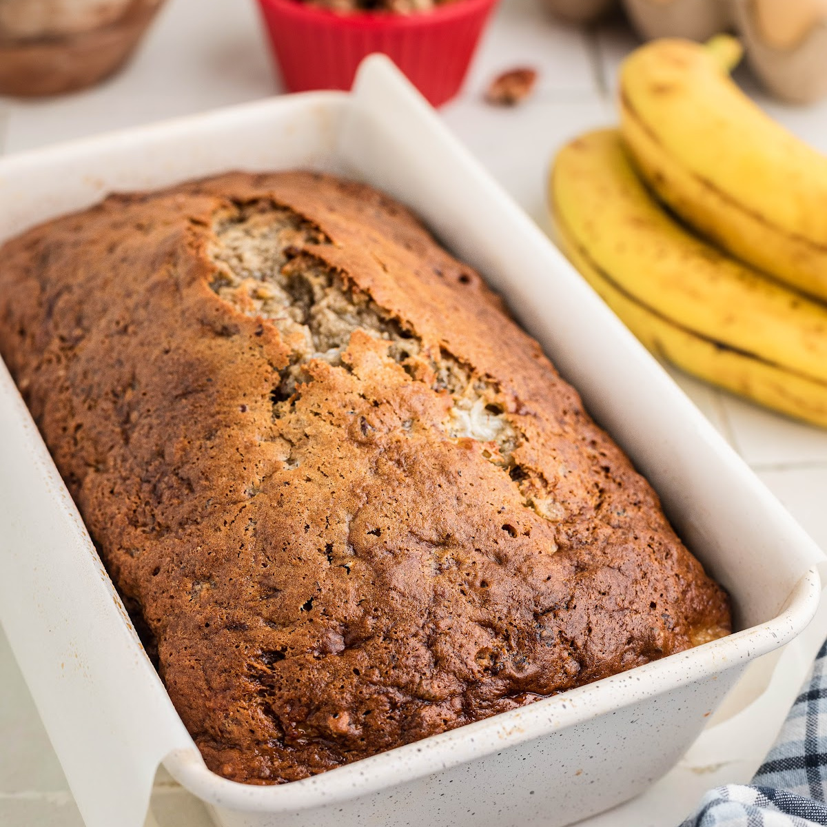 Banana bread with cottage cheese baked in a white loaf pan with a deeply browned, cracked top.