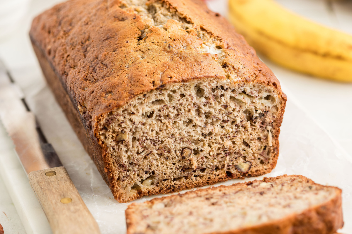 Banana bread with cottage cheese sliced to show the banana and toasted pecans throughout the loaf.
