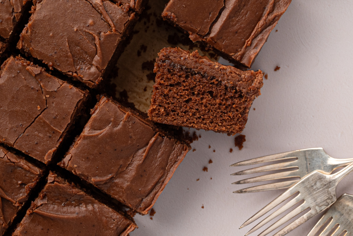Thick Chocolate Texas Sheet Cake with Fudge Frosting Thick slice of chocolate buttermilk Texas sheet cake showing its tender chocolate interior and generous layer of fudge frosting.