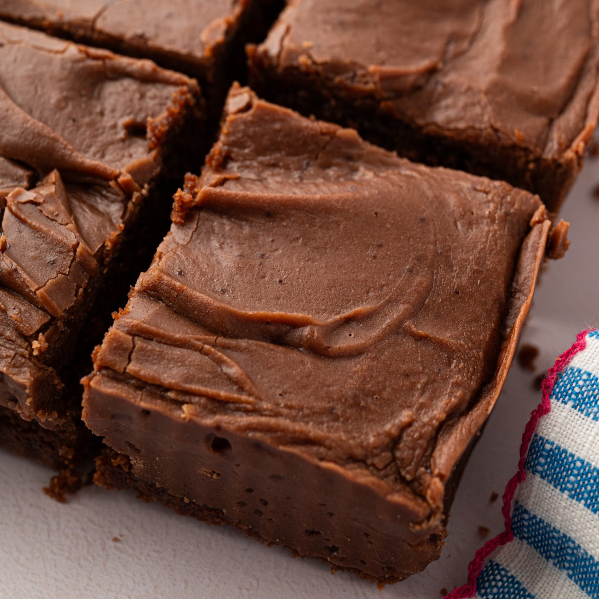 Chocolate buttermilk Texas sheet cake cut into thick squares with a generous layer of brown butter chocolate frosting.