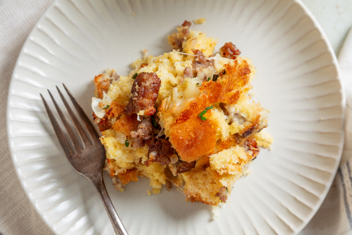 Serving of cornbread breakfast casserole with sausage, melted cheese and browned cornbread