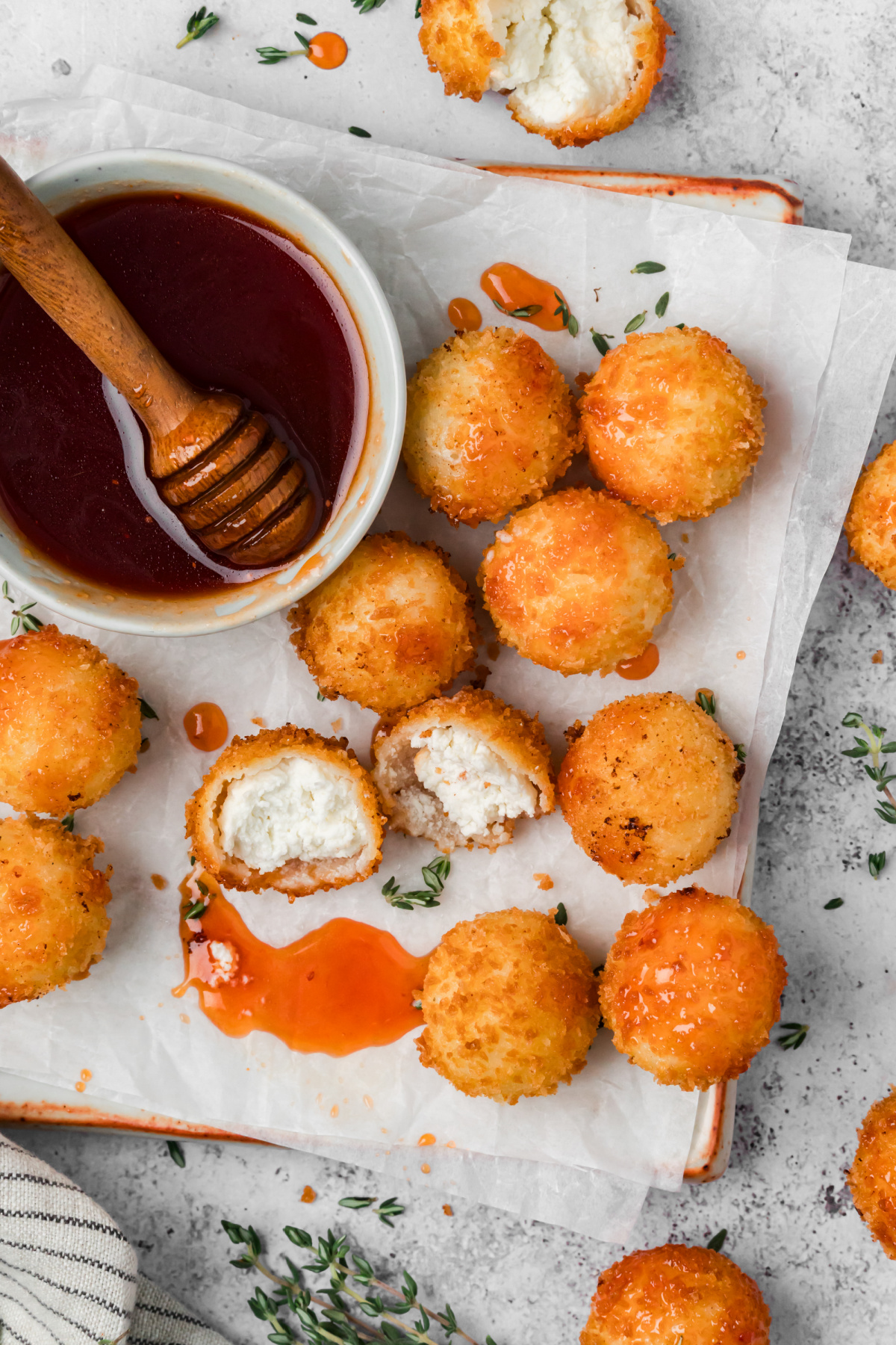 Crispy Goat Cheese Appetizers with Cranberry Hot Honey Overhead view of golden panko-coated goat cheese balls with cranberry hot honey, including two cut-open halves showing the creamy cheese filling.