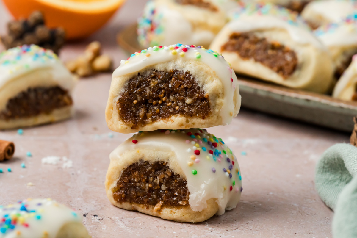 Italian Fig Cookies with Fig and Walnut Filling Close-up of two Italian fig cookies stacked together, showing the moist fig and walnut filling surrounded by tender pastry and topped with vanilla glaze and rainbow nonpareils.