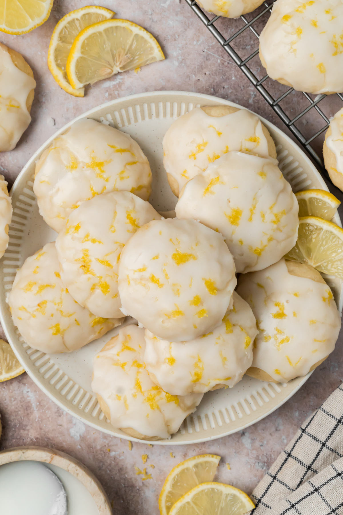 Lemon Glazed Ricotta Cookies on a Serving Plate Lemon glazed ricotta cookies topped with fresh zest on a serving plate with sliced lemons