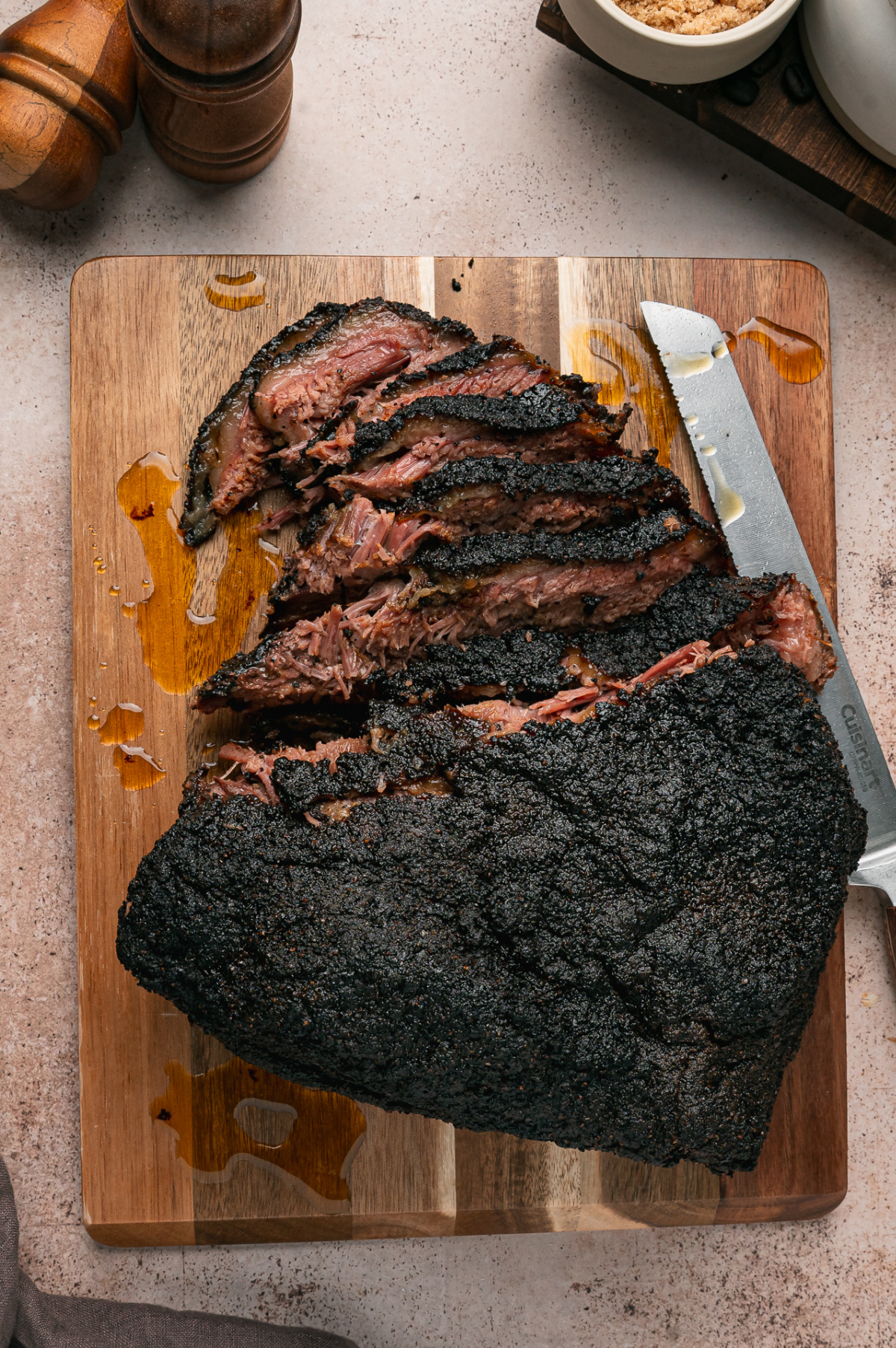 Sliced Coffee Rubbed Oven Brisket with a nearly black coffee crust and tender beef on a wooden cutting board.