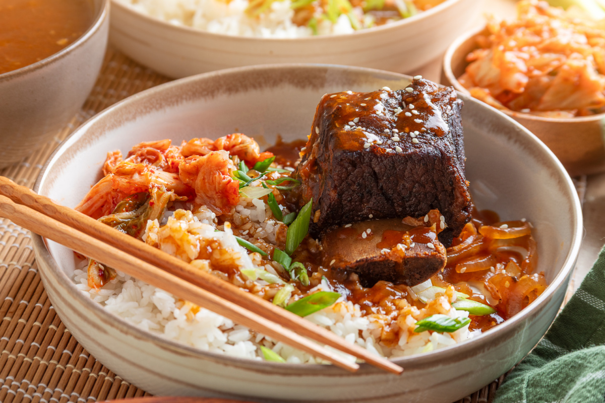 Bone-in Korean short rib coated in gochujang sauce, served over white rice with kimchi, softened onions, and green onions.