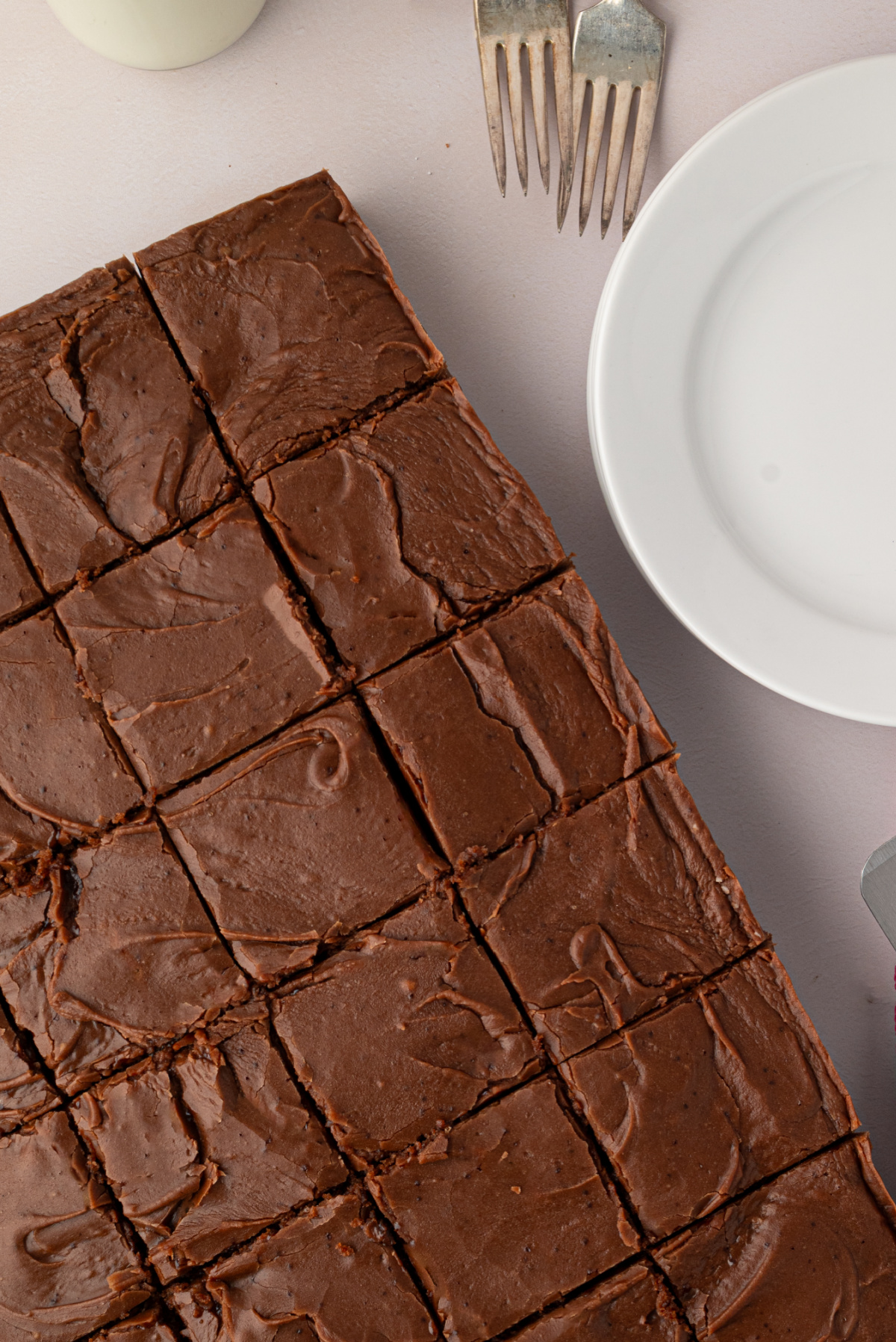 Thick Texas Sheet Cake with Generous Chocolate Frosting Overhead view of a thick chocolate Texas sheet cake cut into squares with swirled chocolate fudge frosting.